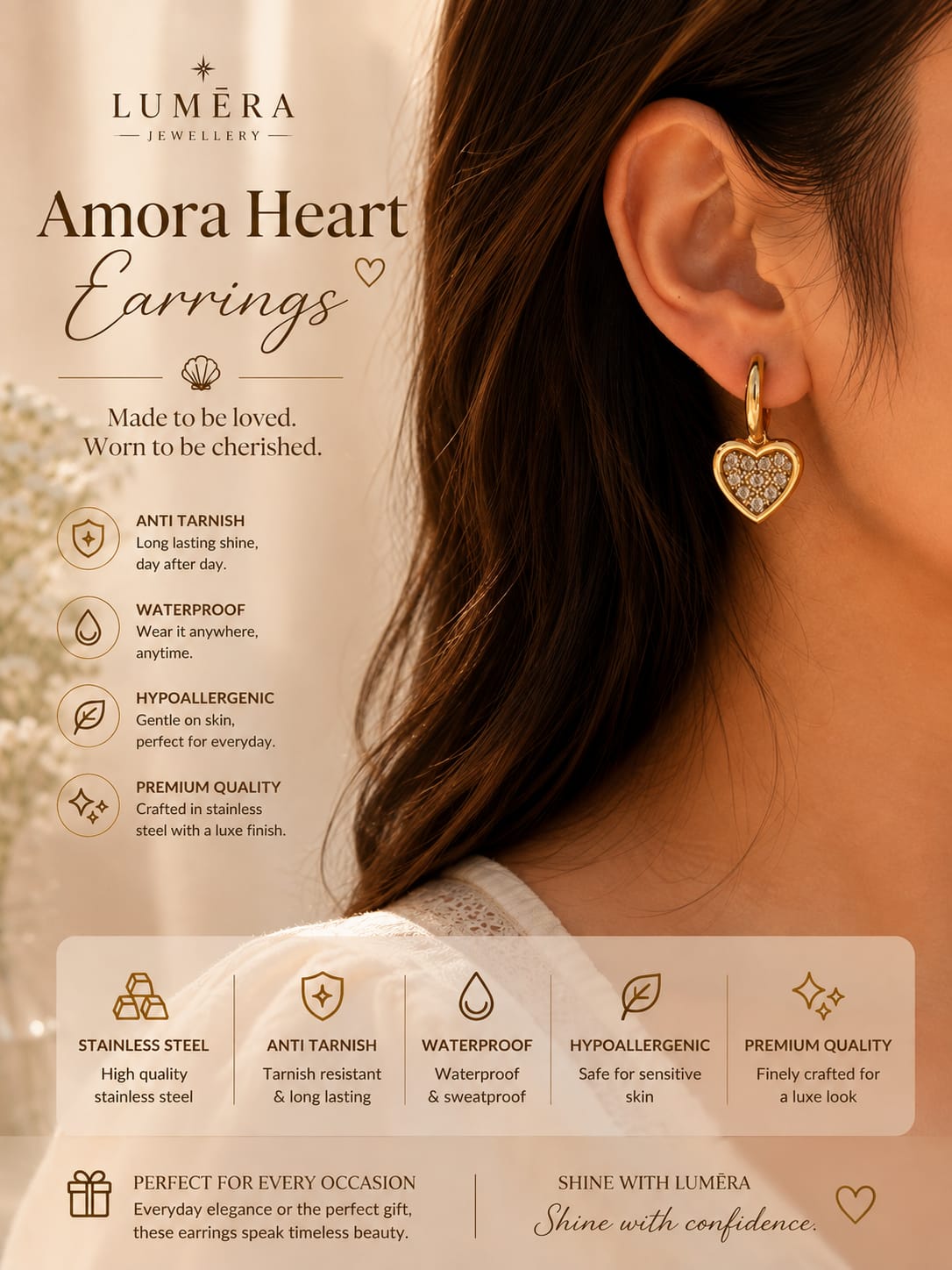 A promotional product graphic for Luméra Amora Heart Earrings, showing a close-up of a woman's ear wearing a gold heart-shaped earring with a clear gemstone. The left side contains product details, including the Luméra brand logo, product name, and feature icons for anti-tarnish, waterproof, hypoallergenic, and premium quality.