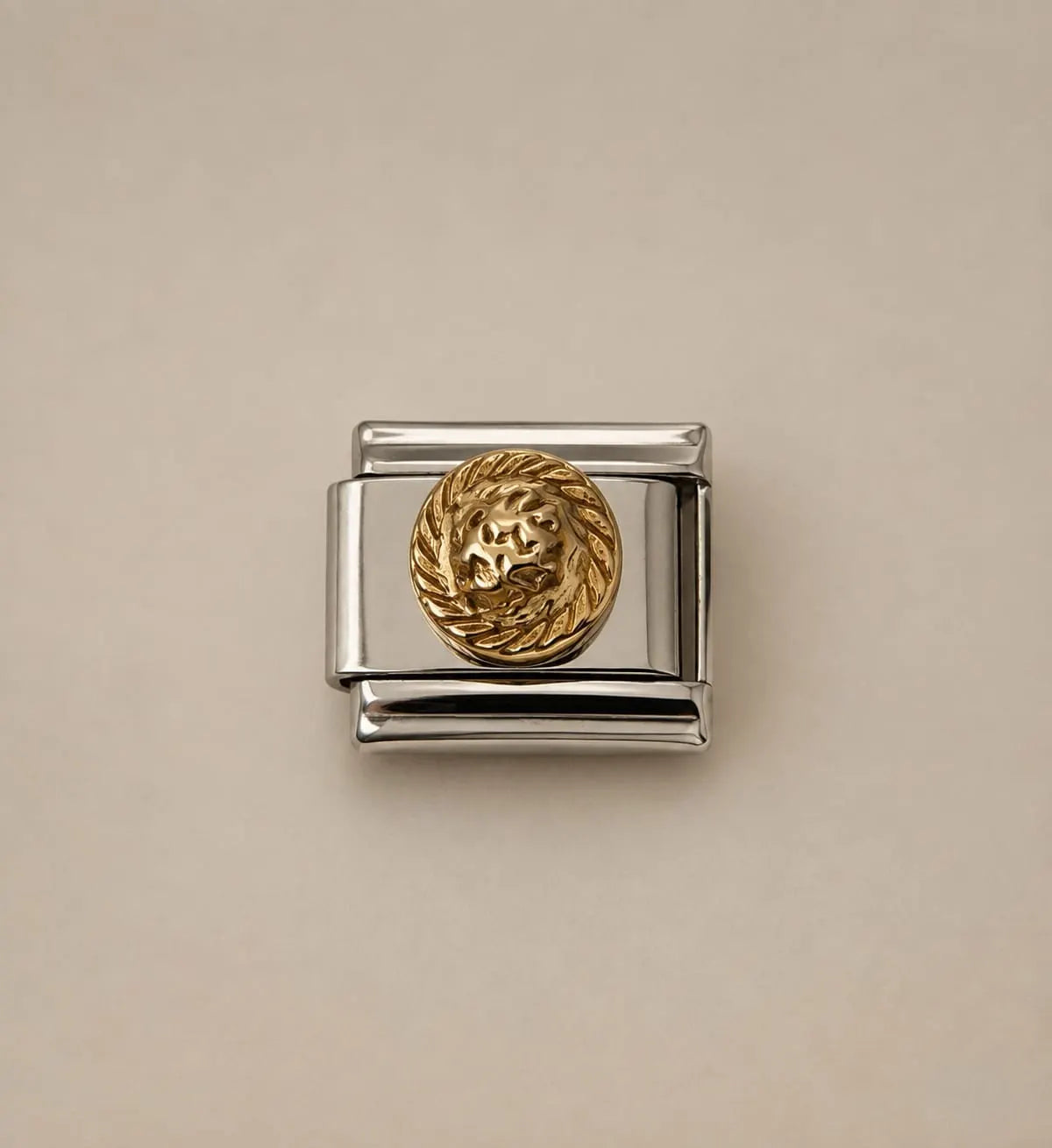 A silver-toned Italian charm link featuring a circular gold-toned lion head medallion, shown on a plain beige background.