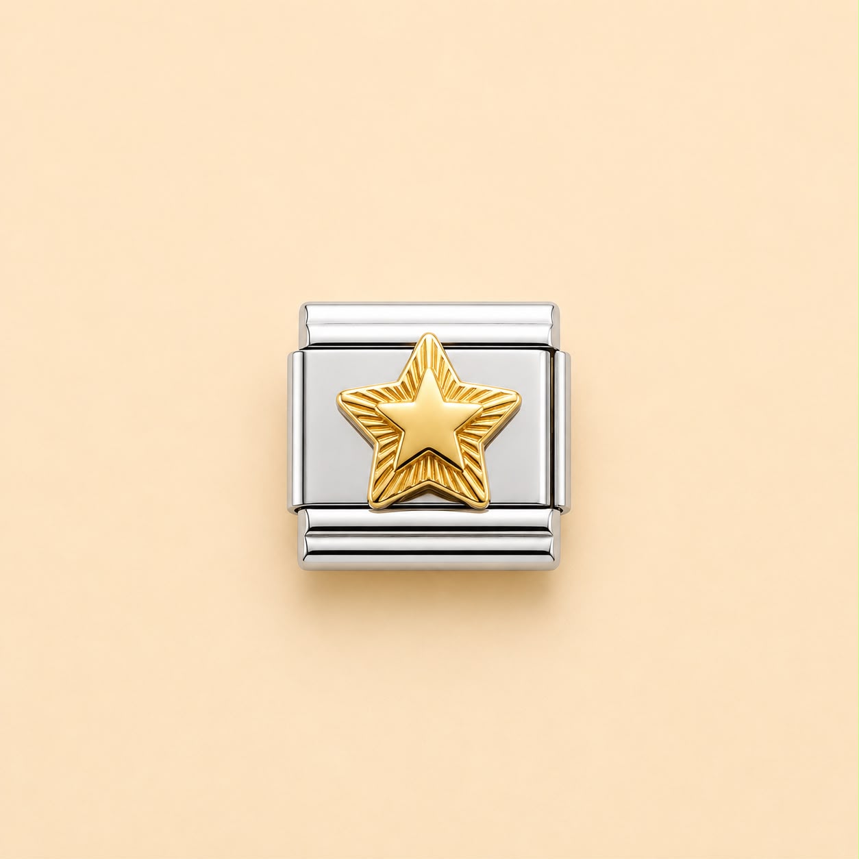 A silver-toned rectangular charm link featuring a textured gold star in the center, displayed on a solid pale peach background.