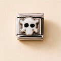 A silver-toned metal charm link featuring a white enamel ghost with black eyes, set against a warm beige background.