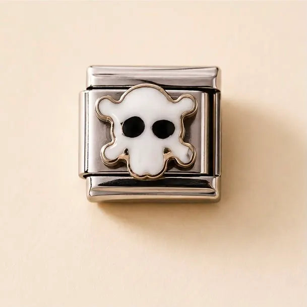 A silver-toned metal charm link featuring a white enamel ghost with black eyes, set against a warm beige background.
