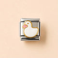 A square silver-toned metal charm link featuring a white duck design with a gold outline and a pink beak, set against a solid pale peach background.